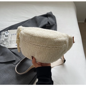 Detail view of a white fleece crossbody bag with textured fabric and woven zipper pull