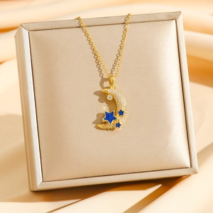 Elegant gold crescent moon necklace with blue stars and sparkling stones on gift box