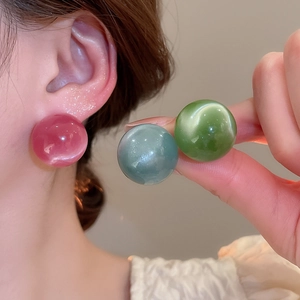 Detailed view of candy-colored round stud earrings in pink, blue, and green resin finish