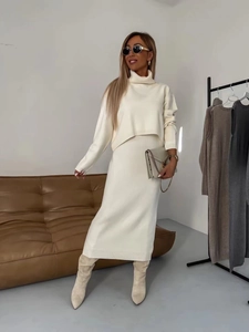 Détail de l'ensemble avec pull à col roulé blanc crème et jupe longue en maille assortie