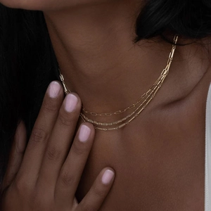 Close-up of three-layered gold stainless steel necklace on model with refined links