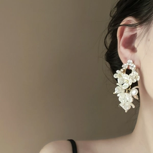 Detailed view of floral beaded tassel earrings with white pearls on a model