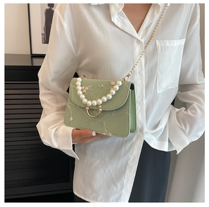 Detail view of sage green bag with floral embroidery and pearl handle strap