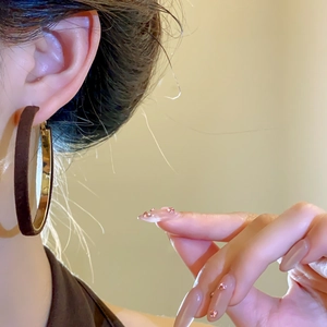 Close-up of elegant gold hoop earrings worn by a model with manicured nails