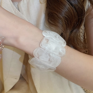 Close-up of a wide acrylic stretch bracelet with white marble patterns on model's wrist
