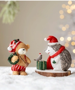 Miniature resin bear and hedgehog figurines on snow with festive Christmas decorations