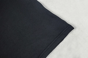 Detailed close-up of black knit dress fabric with white trim and precision stitching