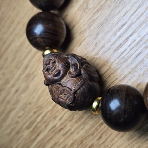 Gros plan de perles en bois d'agar avec sculpture de Bouddha et espaceurs dorés fins