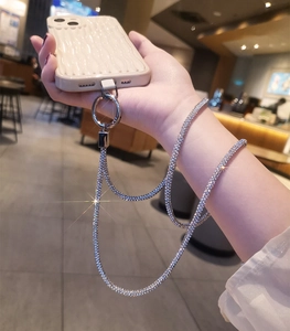 Close-up of luxury rhinestone phone strap and ripple texture case in a cafe setting