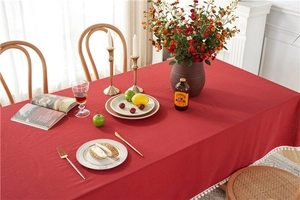 Detail of red cotton tablecloth featuring decorative white pom-pom trim and woven texture