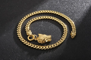 Detailed close-up of golden stainless steel wolf head motifs on a heavy cuban chain necklace