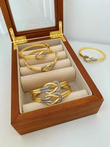 Nahaufnahme eines goldenen Knotenknoten-Armreifs mit silbernen Kristallen in einer Holzbox