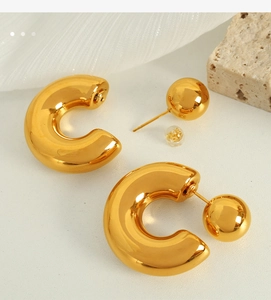 Close-up of polished gold-plated thick C-shape earrings with sphere detail
