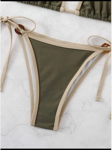 Detail of olive green bikini bottoms with side tie straps and tortoiseshell rings