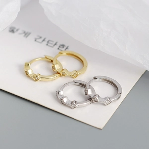 Macro view of gold and silver rhombic geometric earrings with sparkling zircon inlay