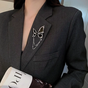 Détail d'une broche papillon noire avec glands argentés sur une veste de costume grise