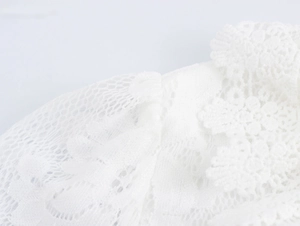 Gros plan détaillé de la broderie en dentelle florale blanche sur une robe longue
