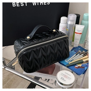 Dettaglio della trousse nera plissettata con cerniera dorata e texture in pelle PU
