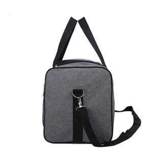 Detail view of grey oxford fabric travel bag with adjustable black shoulder strap and metal hooks