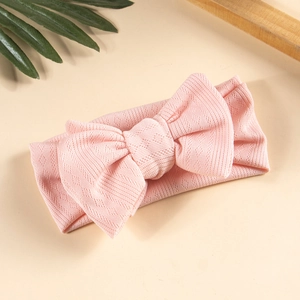 Close-up of pink knitted baby headband featuring a large double bow with diamond texture