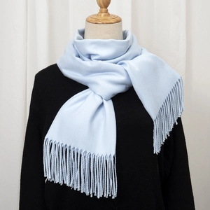 Detail of light blue faux cashmere scarf showing soft texture and tassel trim details