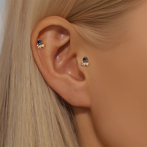 Detail of S925 sterling silver gold stud earring with blue stone and star zircon on ear