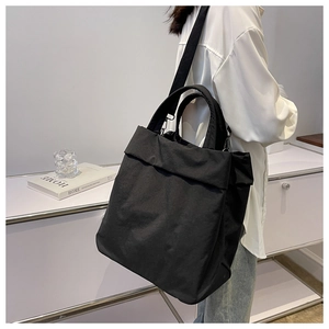 Lifestyle shot of large black nylon tote bag worn over the shoulder with casual outfit