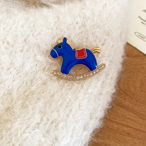 Close-up of blue fabric rocking horse brooch with sparkling rhinestones on soft textile