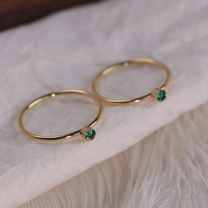 Elegant gold titanium steel rings with dark green zircon stones on soft white fabric