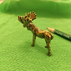 Macro shot of golden elk metal ornament showing detailed casting texture and small size
