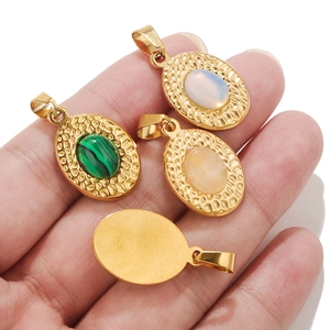 Oval stainless steel gold pendants with turquoise and opal stones held in hand