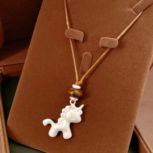 Détail du pendentif licorne en résine avec cordon tressé dans un écrin en velours