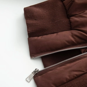 Detail of dark brown puffer jacket with ribbed cuffs and durable metal zipper