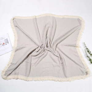 Coperta in mussola di cotone grigio chiaro per neonati con eleganti nappe color crema