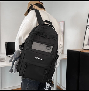 Dettaglio dello zaino in nylon nero con tasca a rete ed etichetta logo KDMILD