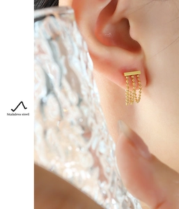Detailed macro view of gold-tone stainless steel stud earrings with three bead tassels