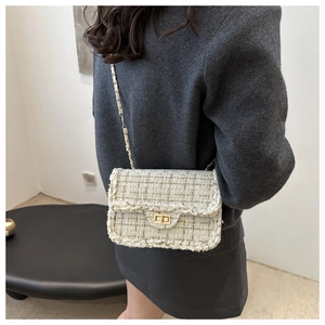 Detail of tweed flap bag with gold chain strap worn by a model in a minimalist setting