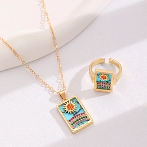 Detail of tarot card Sun necklace and ring set in golden finish on white background