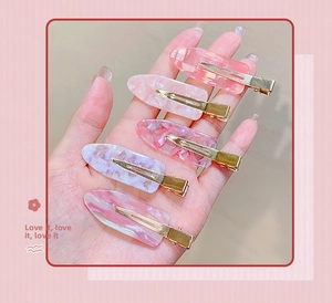 Set of five pink marble textured resin duckbill hair clips shown being held in hand