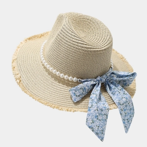 Detail of straw sun hat featuring elegant pearl trim and floral blue ribbon bow
