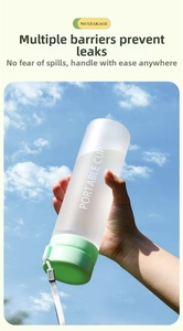 Frosted portable water bottle with green lid and grey strap held against a blue sky