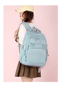 Side view of a light blue waterproof student backpack worn by a model on pink background