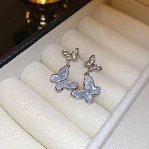 Macro detail of silver butterfly earrings with blue gradient beads and crystals