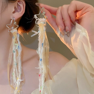 Boucles d'oreilles étoile à longs pompons avec rubans en organza et dentelle sur un mannequin