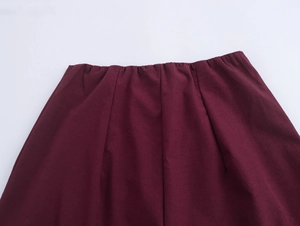 Detailed close-up of elastic waist with pleats on burgundy straight-leg trousers