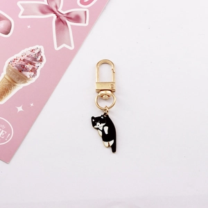 Detail of cute black and white enamel cat keychain with golden metal finish and ring