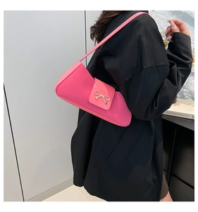 Detailed close-up of pink shoulder bag with a polished metal bow buckle accent