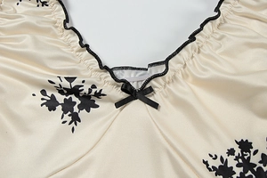 Close-up of V-neckline with floral print, black lettuce edge, and ribbon bow detail