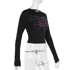 Dettaglio della farfalla rosa e strass sulla maglia nera aderente a maniche lunghe
