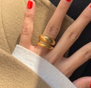 Detail showing two gold stacked chunky dome and thin rings on a hand for daily style